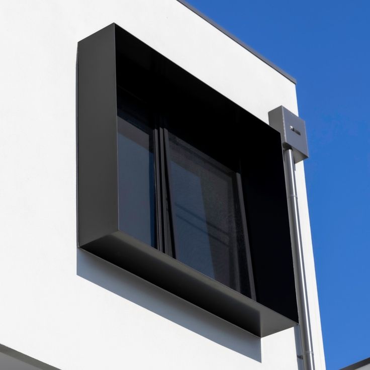 Projecting black aluminium window surround framing an exterior window